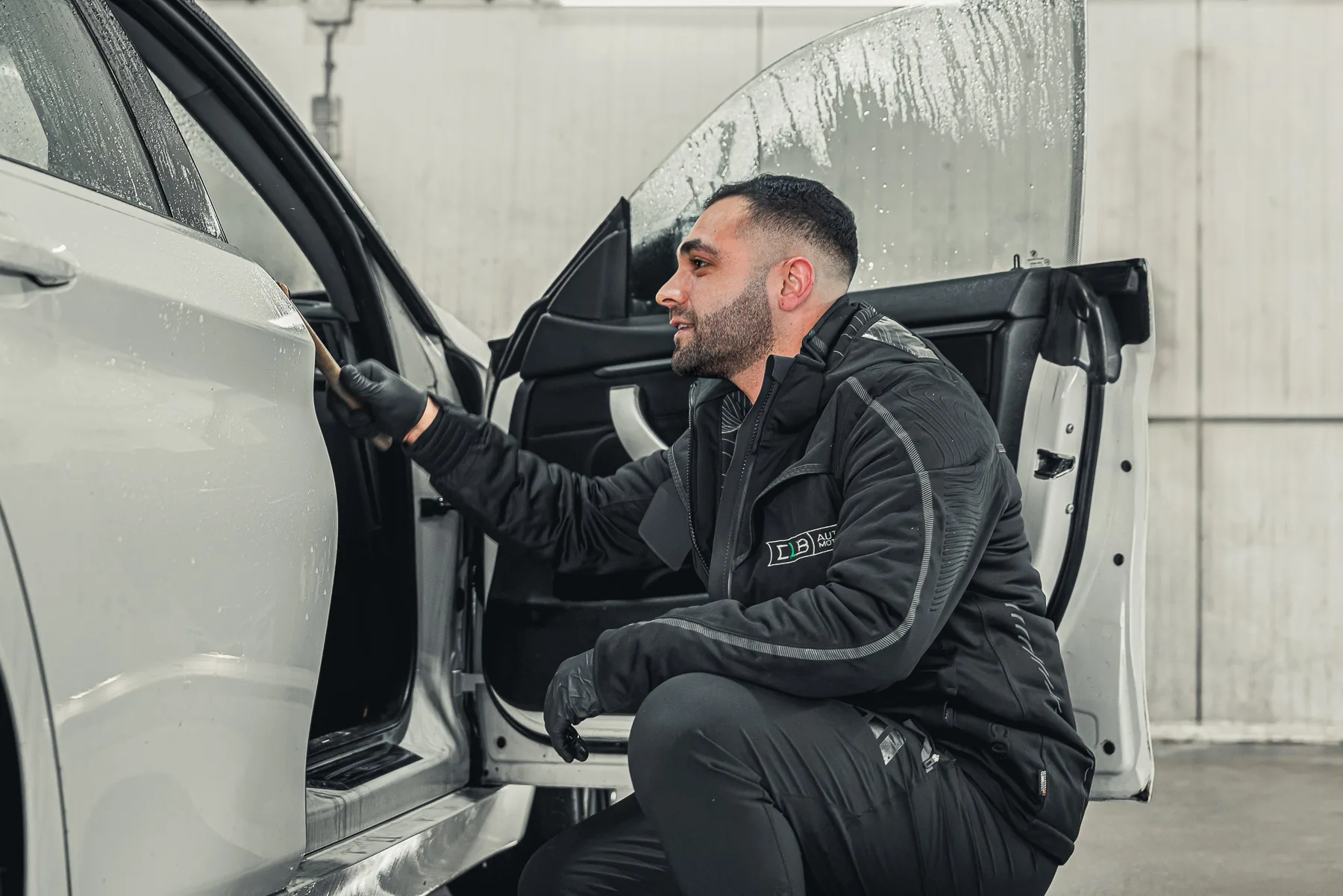Een CLB-medewerker werkt bij het geopende portier van een auto